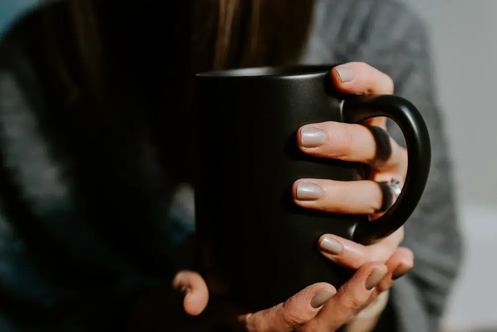Submissive woman holding out coffee mug- Dom sub BDSM rituals